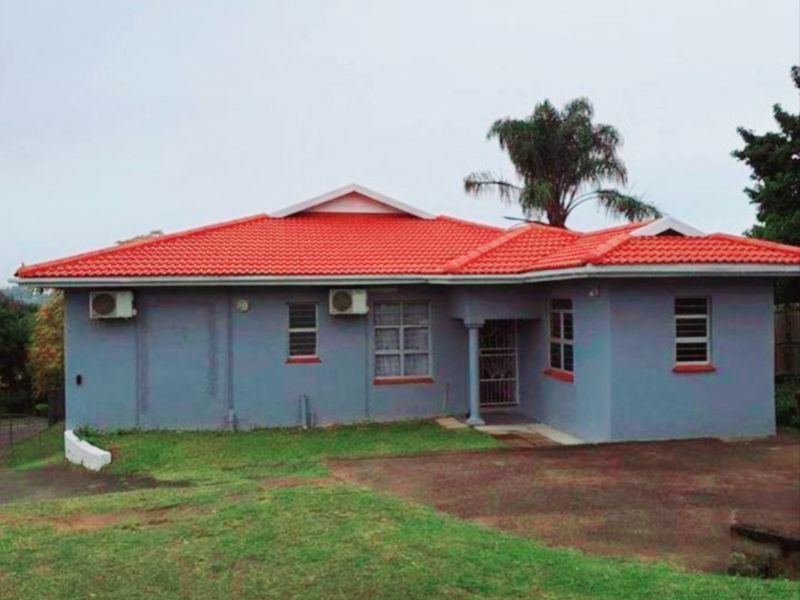 Front elevation of a single-story house featuring a tiled roof, exterior air conditioning units, and a paved driveway area.