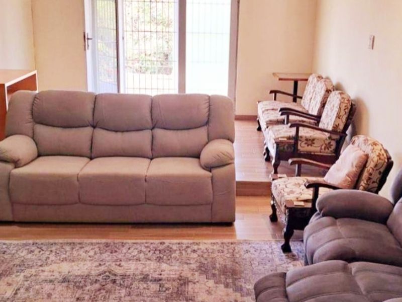A living room area featuring a raised floor section and a sliding glass door with security gate leading to the exterior.