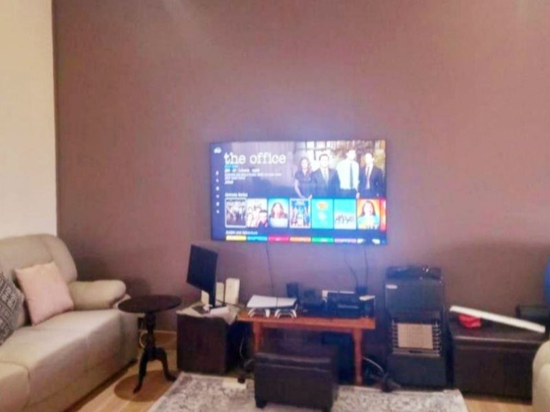 A living room featuring a wall-mounted television and neutral wall finishes.