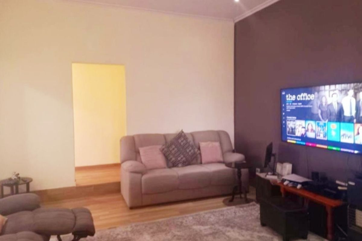 A living room featuring laminate flooring, recessed lighting, and a neutral color palette with an accent wall.