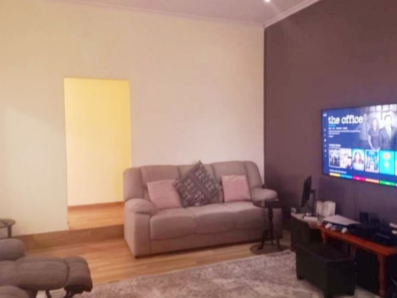 A living room featuring laminate flooring, recessed lighting, and a neutral color palette with an accent wall.