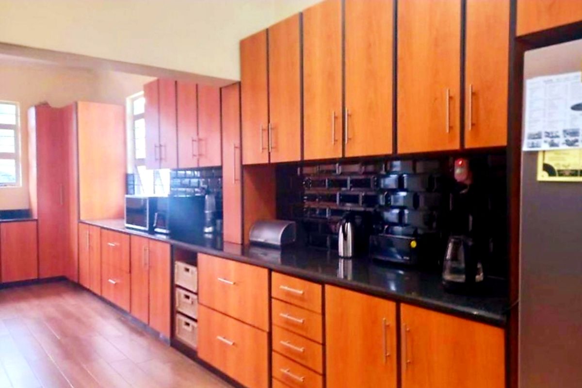 A functional kitchen featuring extensive wood-look cabinetry, dark granite countertops, and a tiled backsplash, providing ample storage and workspace.