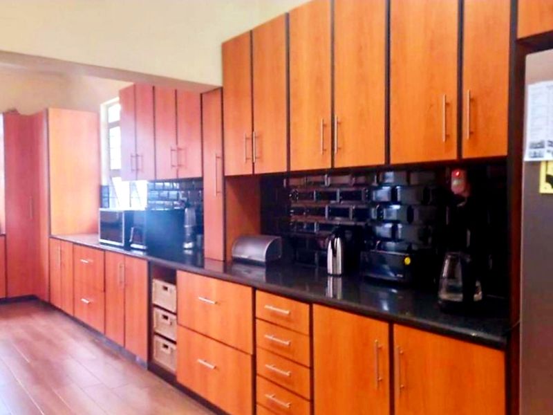 A functional kitchen featuring extensive wood-look cabinetry, dark granite countertops, and a tiled backsplash, providing ample storage and workspace.