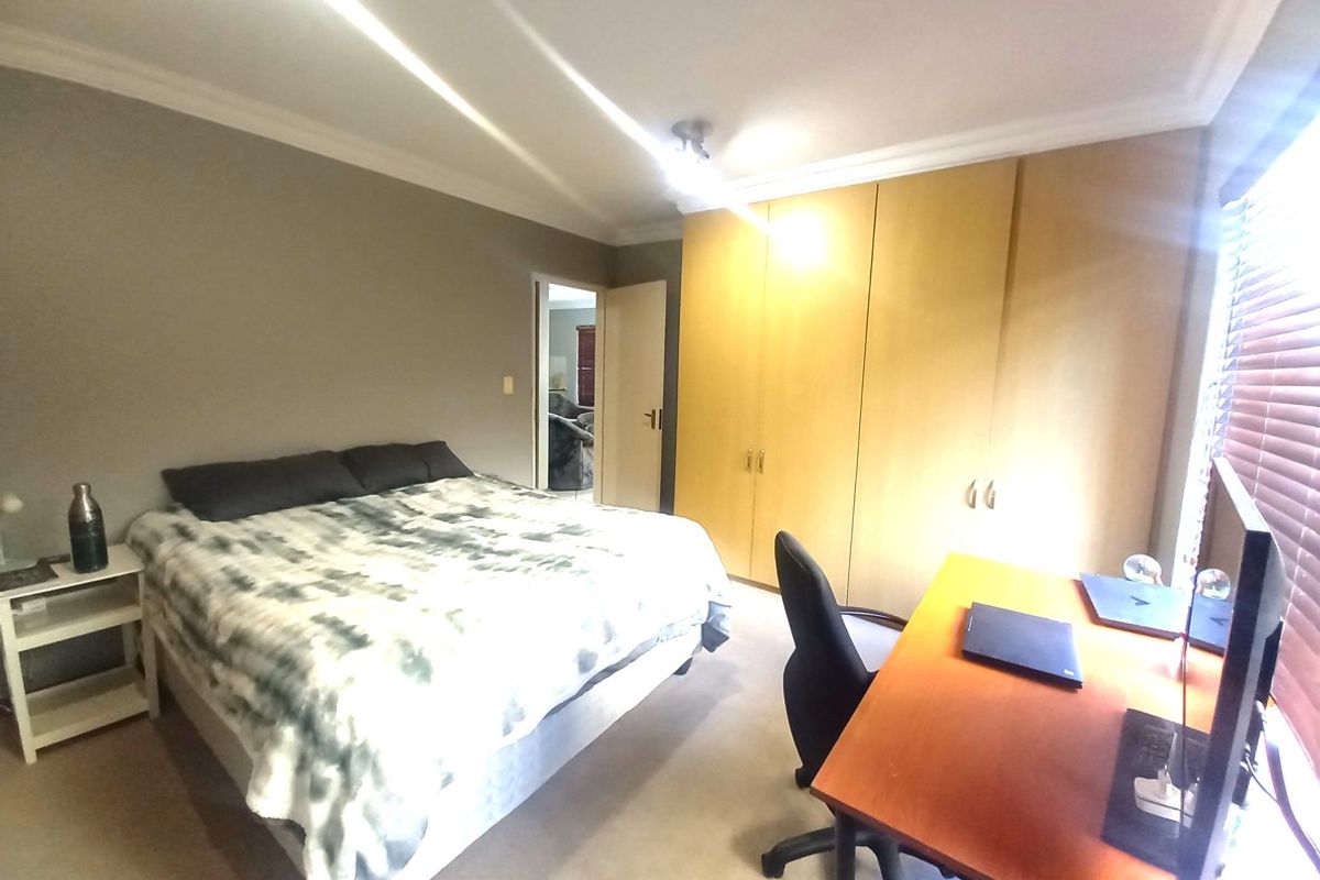 A bedroom featuring built-in wooden cupboards, neutral wall finishes, and venetian blinds, offering a functional space with potential for modern updates.
