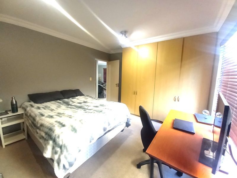 A bedroom featuring built-in wooden cupboards, neutral wall finishes, and venetian blinds, offering a functional space with potential for modern updates.
