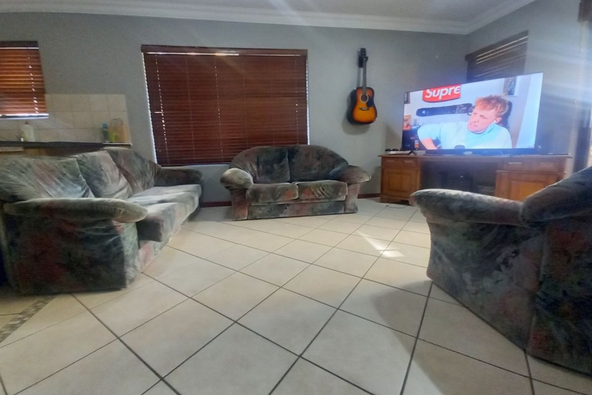 A living room featuring tiled flooring, crown molding, and venetian blinds, providing a functional space for relaxation.
