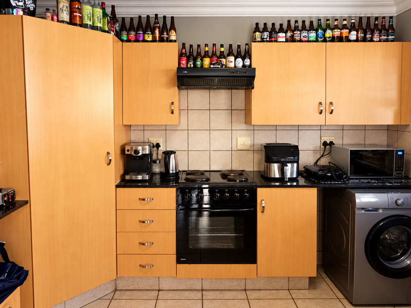 A functional kitchen featuring light wood cabinetry, granite countertops, a tiled backsplash, and integrated appliances including an oven, hob, and extractor fan.