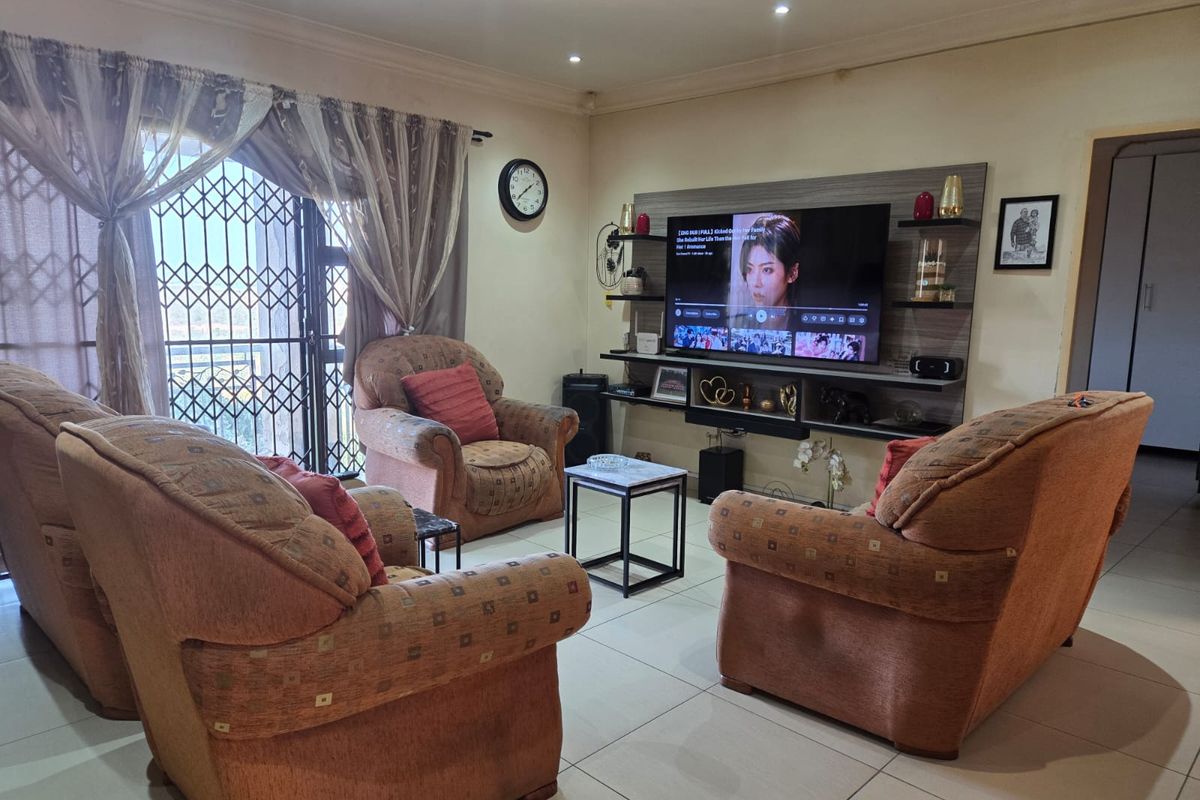 A comfortable living room featuring tiled flooring, recessed downlights, and a built-in media wall unit, providing a functional space for relaxation.