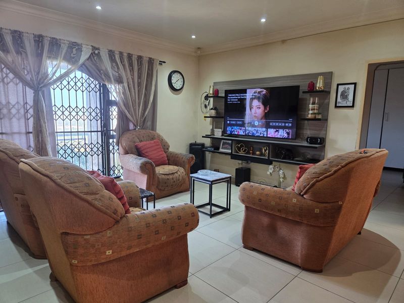 A comfortable living room featuring tiled flooring, recessed downlights, and a built-in media wall unit, providing a functional space for relaxation.