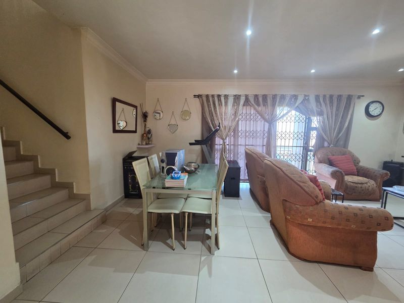 Open plan living and dining area featuring tiled flooring, recessed lighting, and a staircase, with direct access to the exterior through a sliding glass door.