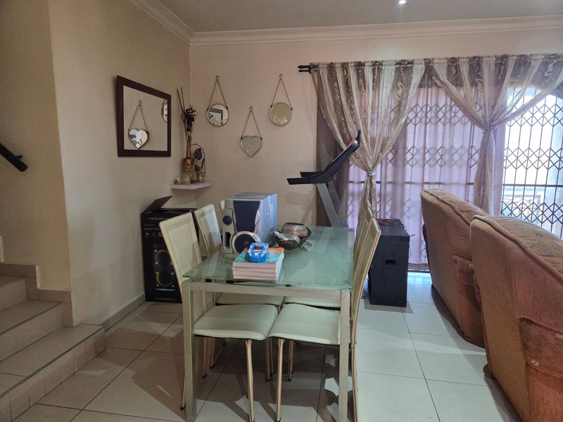 Dining area featuring tiled flooring and a sliding glass door with security gate, providing access to the exterior.
