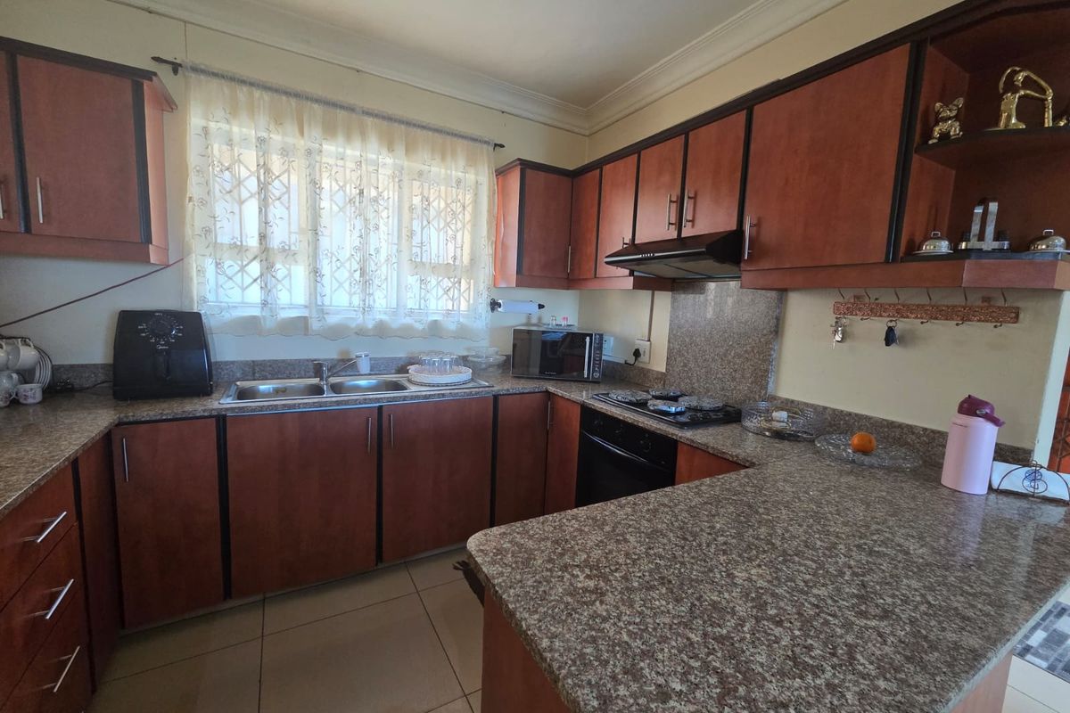 A functional kitchen featuring wood-finish cabinetry, granite countertops, a built-in oven with gas hob, and tiled flooring.