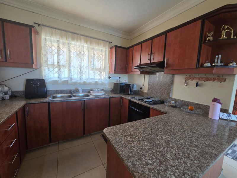 A functional kitchen featuring wood-finish cabinetry, granite countertops, a built-in oven with gas hob, and tiled flooring.