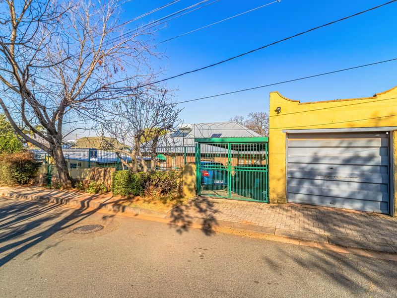 Front exterior view of the property featuring a single garage, paved driveway, and secure metal gate entrance with perimeter fencing.