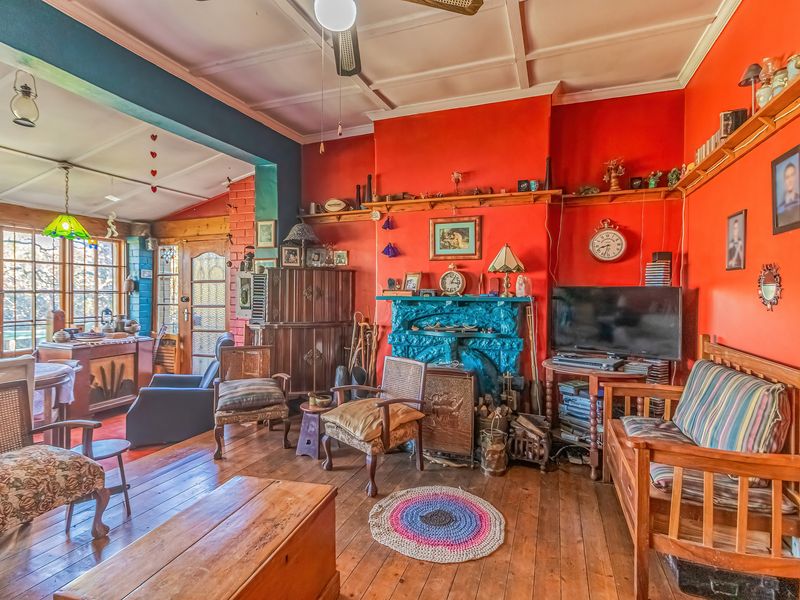 A living room featuring timber flooring, a fireplace, and timber ceiling details, offering a rustic aesthetic with potential for modernization.