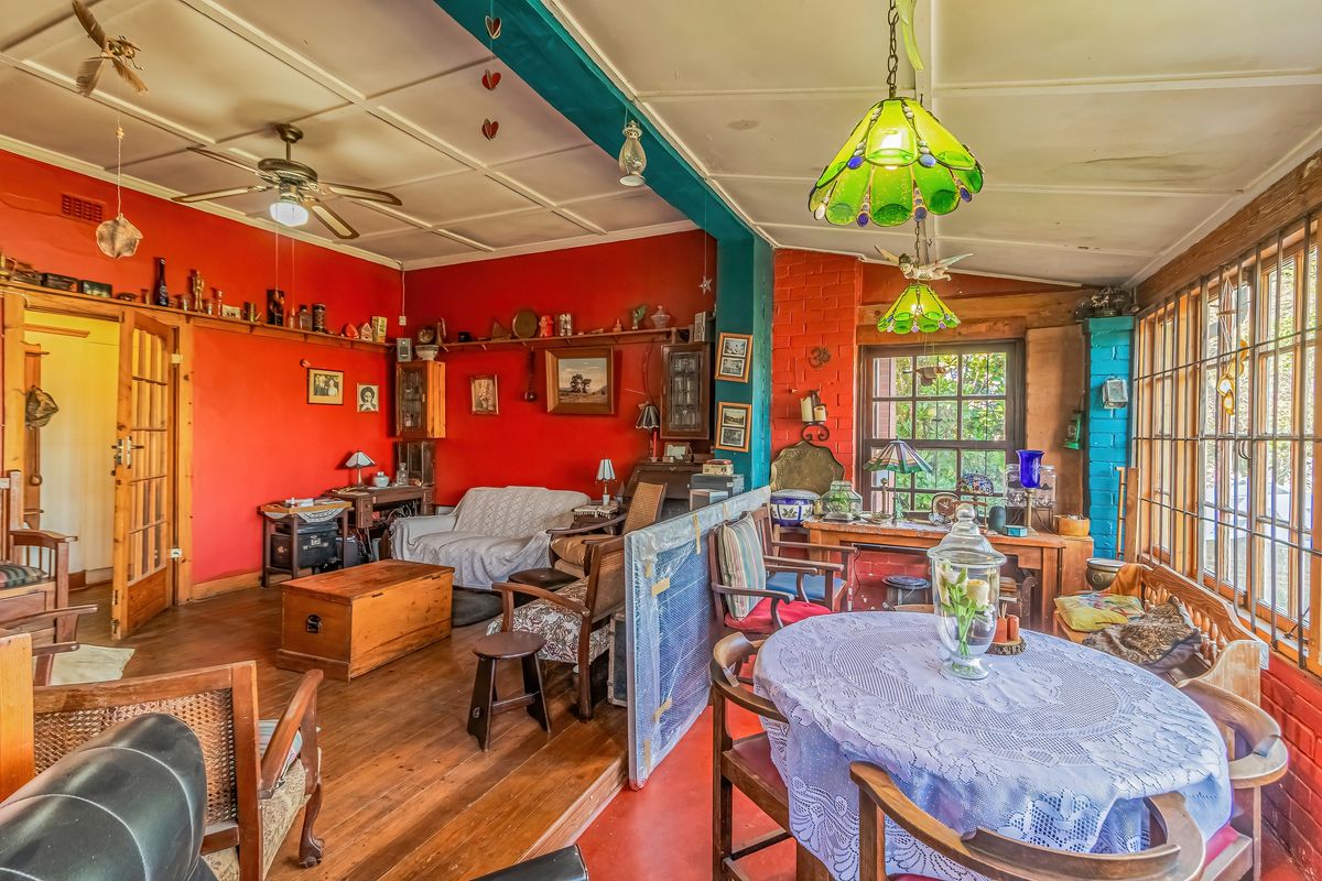 A spacious living area featuring timber flooring, exposed brick elements, and large timber-framed windows, offering a rustic and character-filled living space.