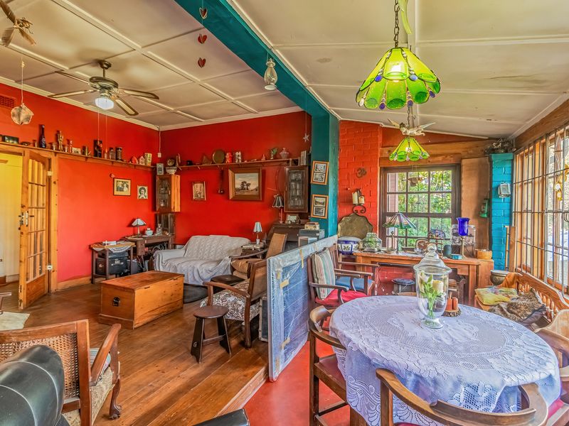 A spacious living area featuring timber flooring, exposed brick elements, and large timber-framed windows, offering a rustic and character-filled living space.