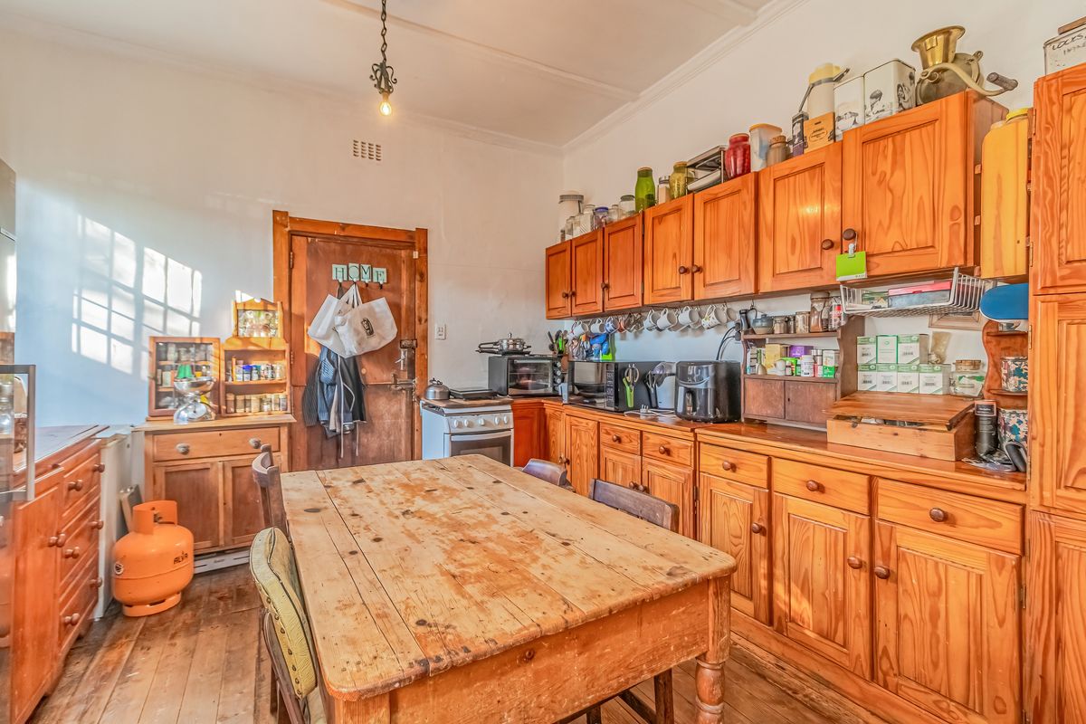A rustic kitchen featuring extensive timber cabinetry, wooden flooring, and a freestanding oven, offering a traditional aesthetic with potential for modernization.