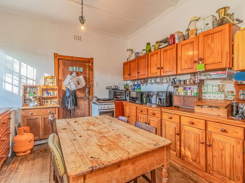 A rustic kitchen featuring extensive timber cabinetry, wooden flooring, and a freestanding oven, offering a traditional aesthetic with potential for modernization.