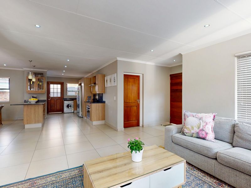 Spacious open-plan living area featuring tiled floors, recessed lighting, and a modern kitchen with built-in cabinetry and island, seamlessly connecting to the living space.