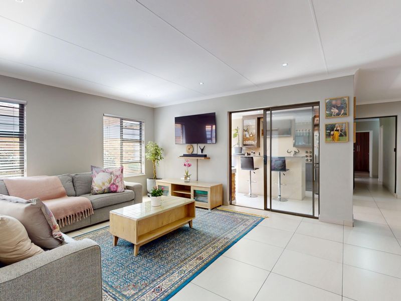 Spacious living room featuring neutral tiled flooring, recessed downlights, and sliding glass doors leading to an adjacent bar or entertainment area.