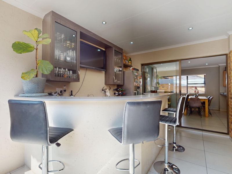 A well-maintained indoor bar area featuring a built-in counter, custom cabinetry, and tiled flooring, with direct access to the adjacent dining space.