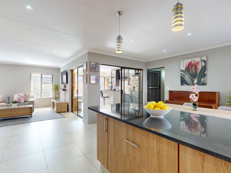 Spacious open-plan living area featuring a modern kitchen island with granite countertops, tiled flooring, and seamless flow to the adjacent living and dining spaces.