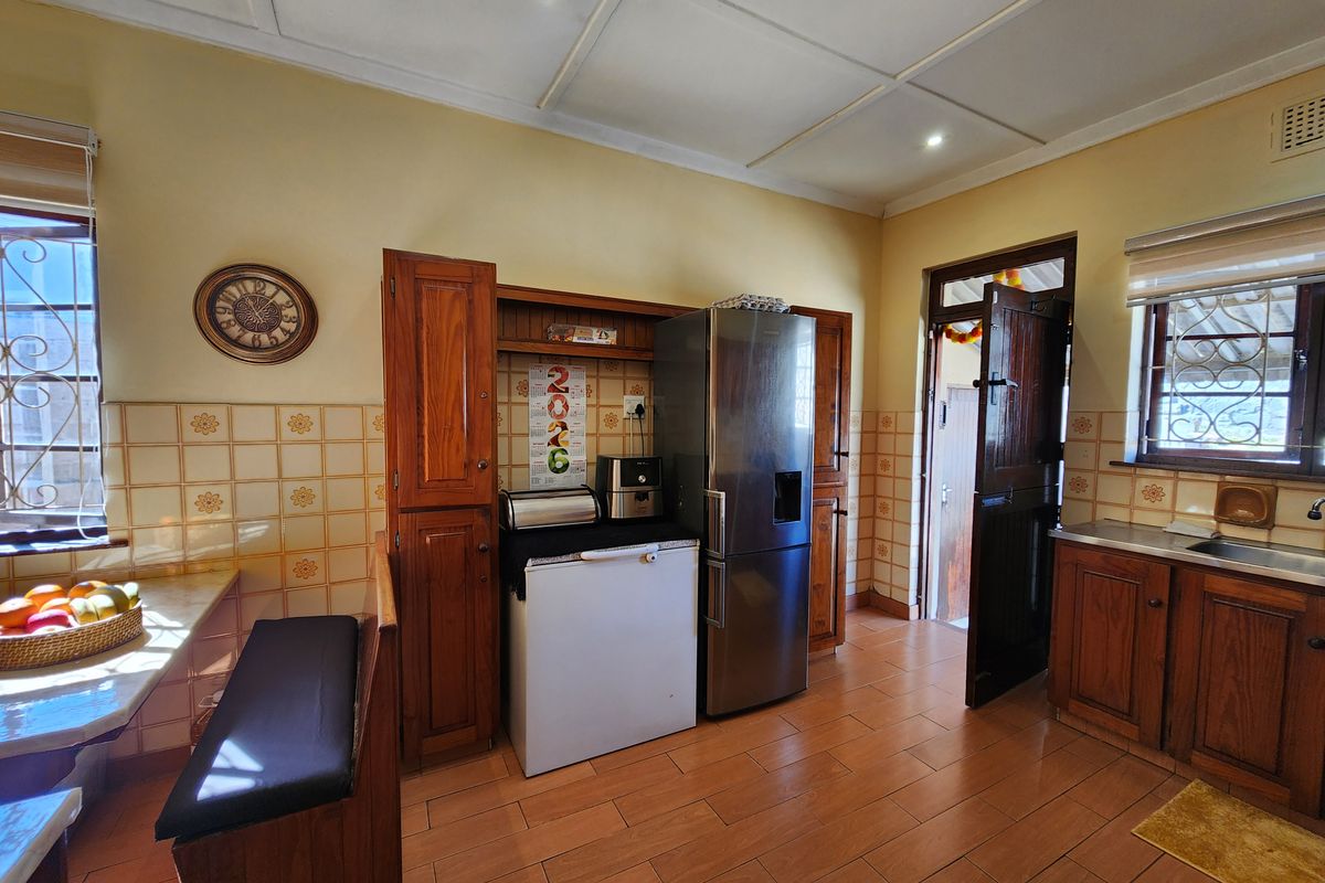 A functional kitchen featuring wooden cabinetry, tiled backsplash, and tiled flooring, with direct access to an exterior doorway.