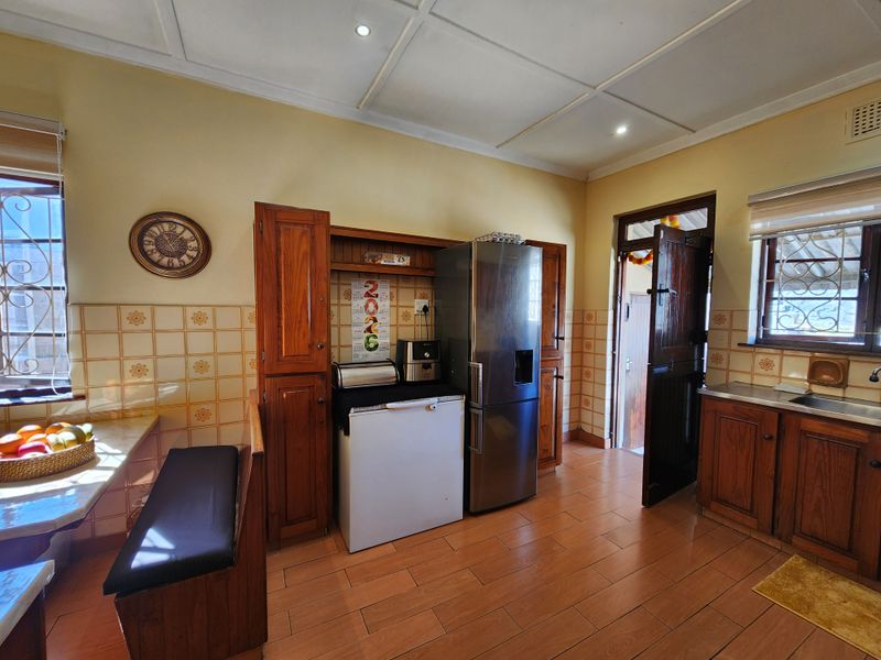A functional kitchen featuring wooden cabinetry, tiled backsplash, and tiled flooring, with direct access to an exterior doorway.
