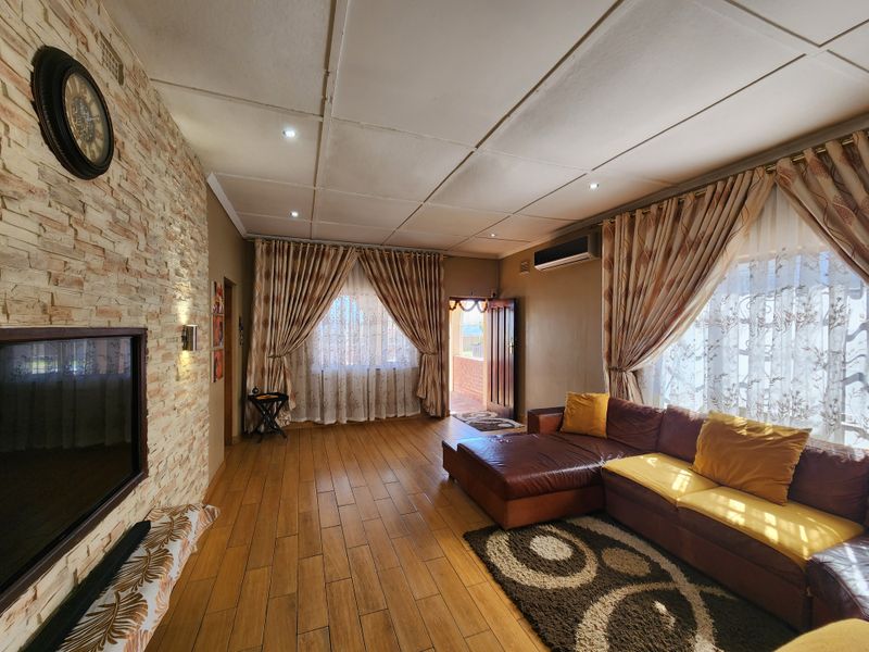 Spacious living room featuring a stone-clad feature wall, wood-look tiled flooring, and a split-system air conditioner, with direct access to an outdoor area.