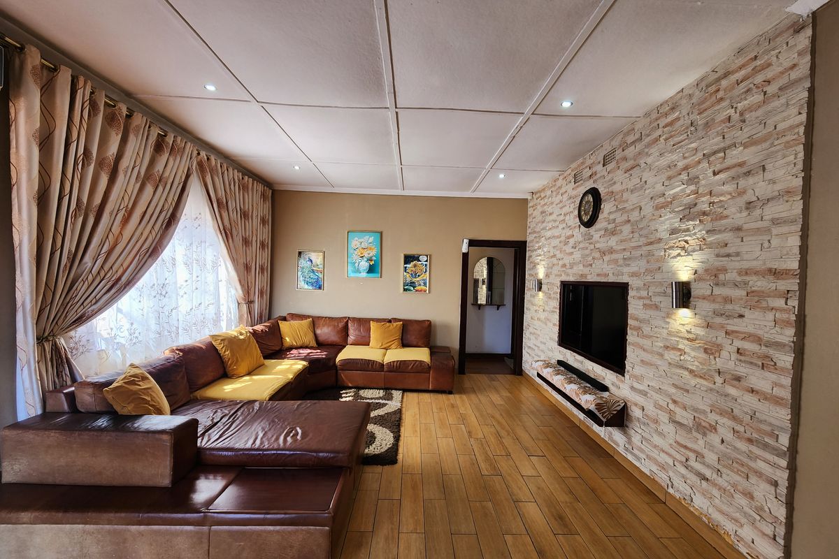 Spacious living room featuring a textured stone veneer feature wall, wood-look tiled flooring, and recessed ceiling lighting.