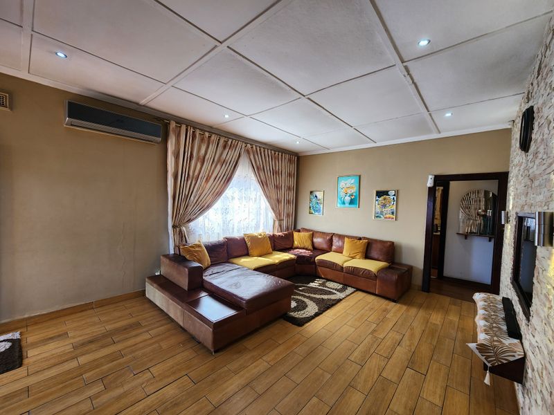 Spacious living room featuring wood-look tile flooring, a stone-cladding feature wall, and a split-system air conditioner.