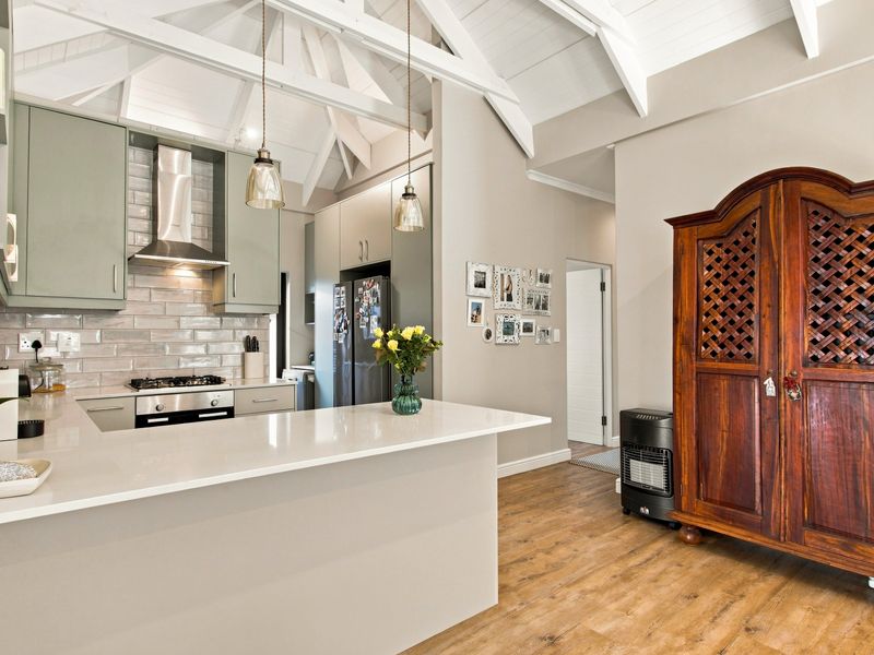 Modern open-plan kitchen featuring quartz countertops, subway tile backsplash, and vaulted ceilings with exposed rafters, creating a bright and spacious living environment.