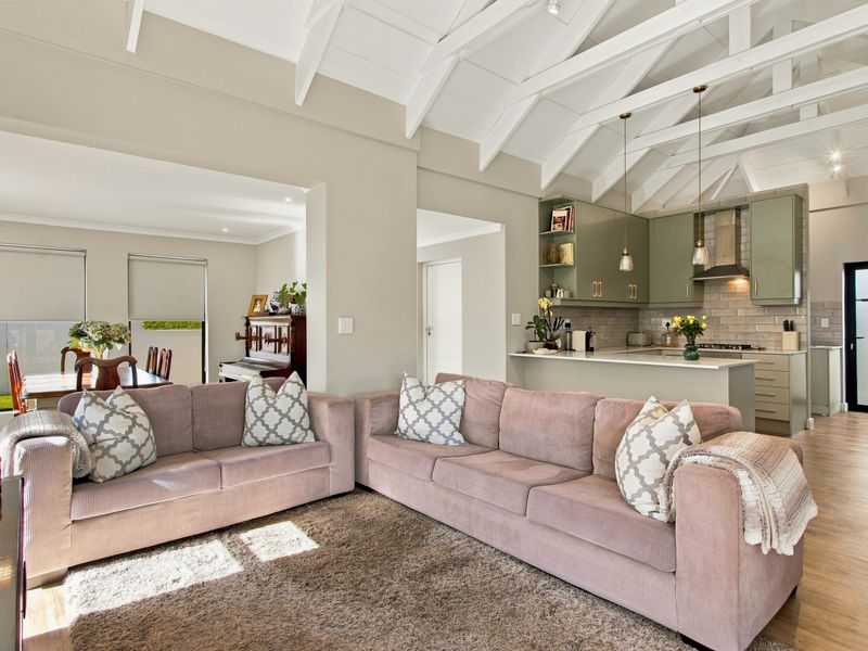Spacious open-plan living and kitchen area featuring vaulted ceilings with exposed beams, modern cabinetry, and a seamless flow to the dining space.