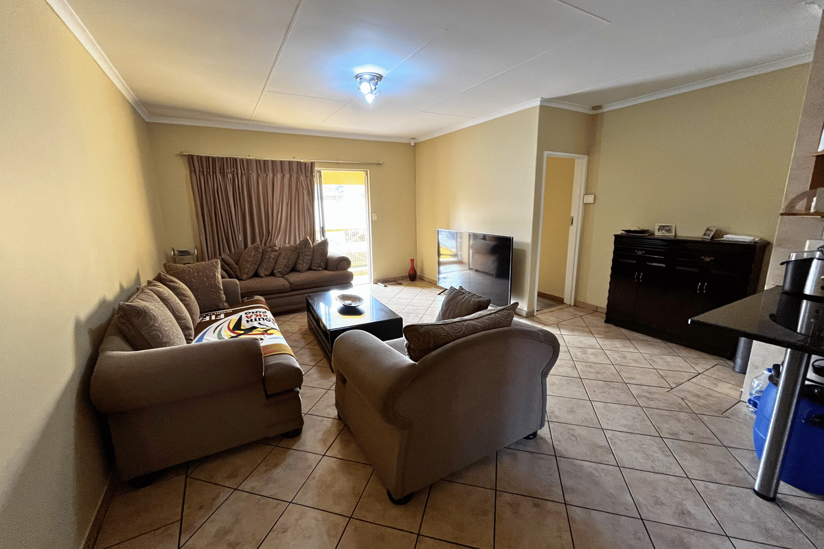A spacious living room featuring tiled flooring, coved ceilings, and a sliding door providing access to the outdoor area.