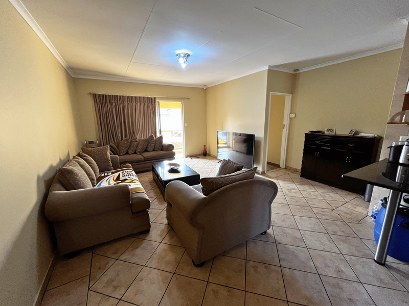 A spacious living room featuring tiled flooring, coved ceilings, and a sliding door providing access to the outdoor area.