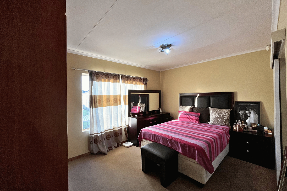 A standard bedroom featuring carpeted flooring, a built-in cupboard, and neutral wall tones, offering a functional and comfortable living space.