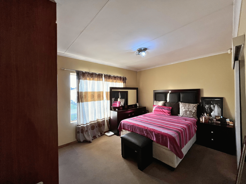 A standard bedroom featuring carpeted flooring, a built-in cupboard, and neutral wall tones, offering a functional and comfortable living space.
