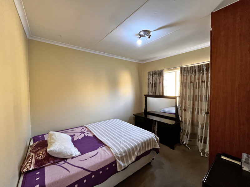 A standard bedroom featuring a built-in cupboard, neutral wall finishes, and a ceiling light fixture.