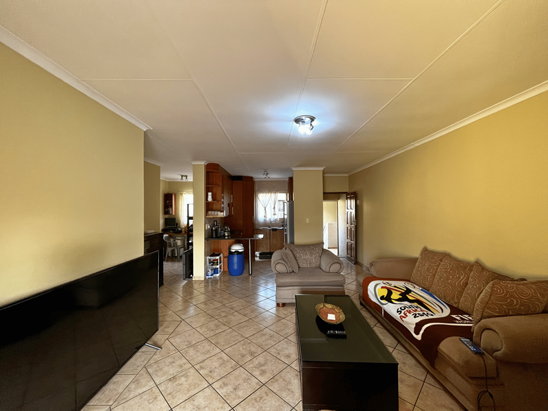 Open-plan living and kitchen area featuring tiled flooring and neutral wall finishes, providing a functional layout for daily living.