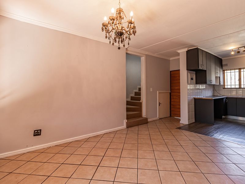 Open plan living and kitchen area featuring tiled floors, built-in cabinetry, and a staircase leading to the upper level.