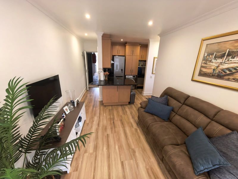 Open-plan living area featuring a modern kitchen with granite countertops, built-in cabinetry, and laminate flooring, seamlessly flowing into the lounge space.