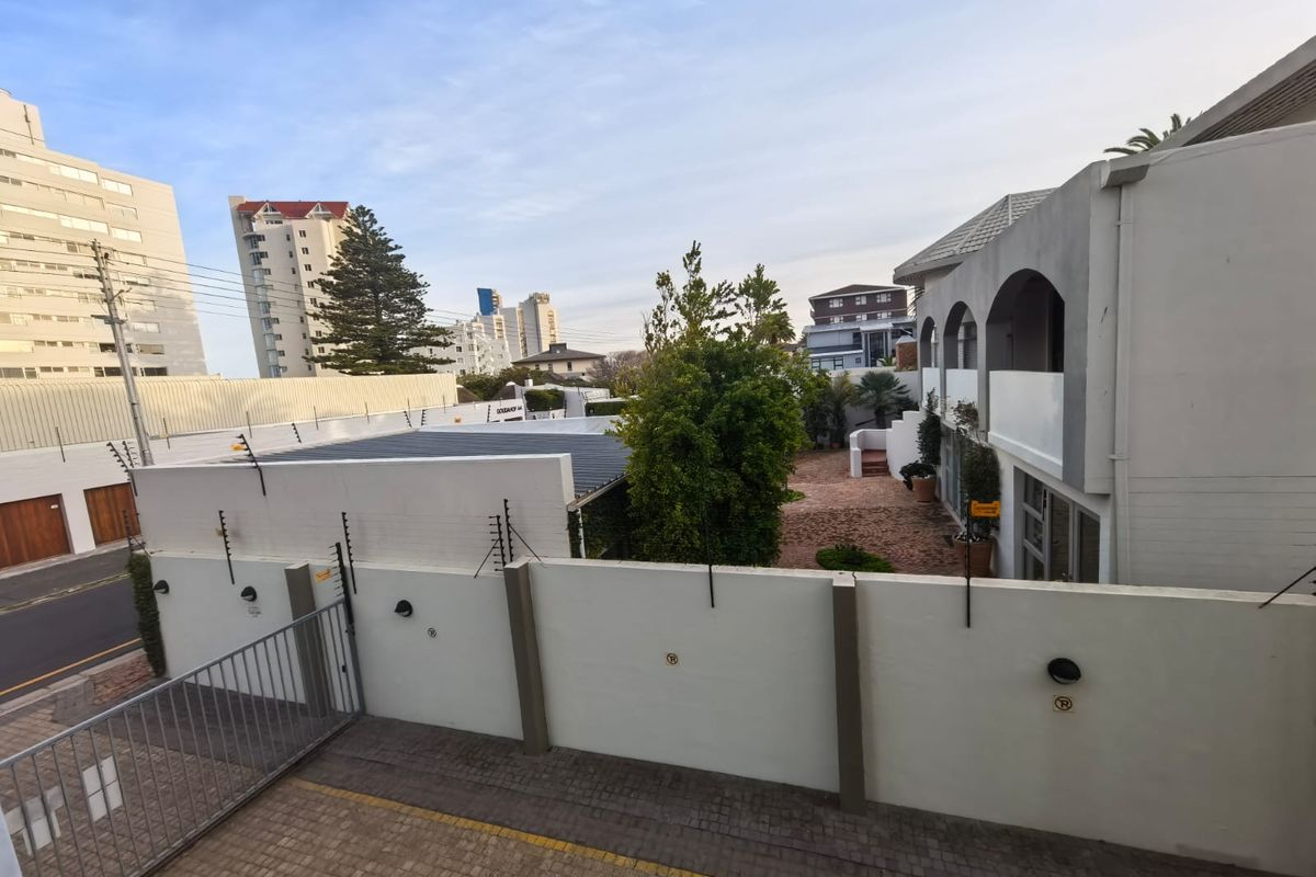 An elevated view of the apartment complex rear courtyard, featuring paved areas, boundary walls with electric fencing, and exterior lighting.