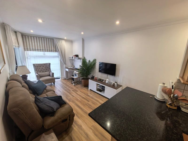 Open plan living area featuring laminate flooring, recessed downlighting, and a granite kitchen countertop, creating a functional and cohesive space.