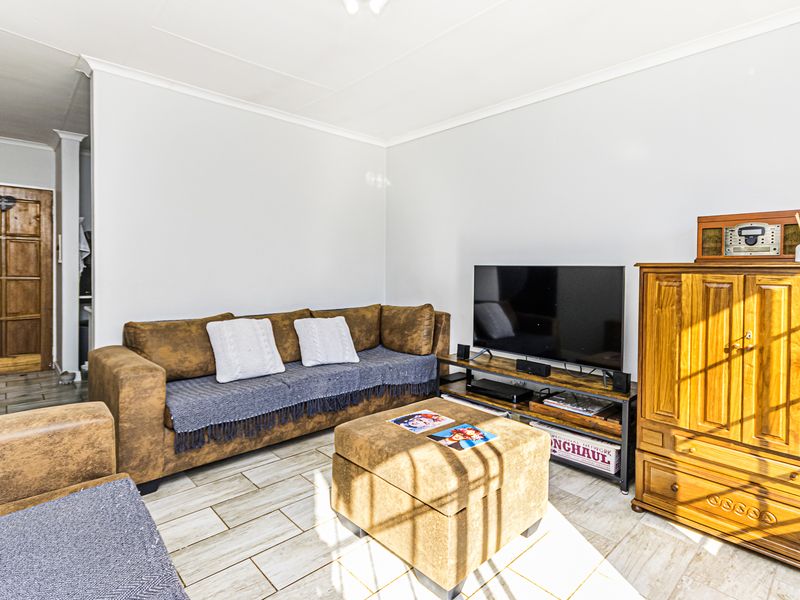A comfortable living room featuring light-toned tiled flooring, a classic timber panelled door, and neutral wall finishes.