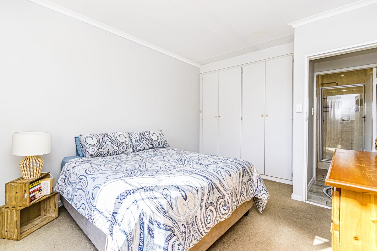 A bedroom featuring built-in cupboards, carpeted flooring, and an en-suite bathroom access.