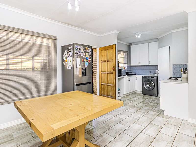 Open-plan kitchen and dining area featuring tiled flooring, white cabinetry, and a functional layout with integrated appliances.
