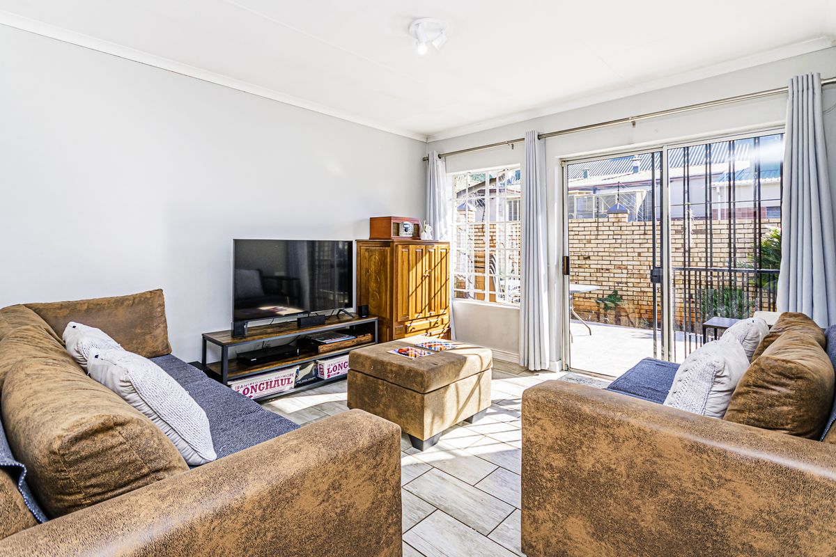 Bright living room featuring tiled flooring and large sliding glass doors providing direct access to the rear patio area.