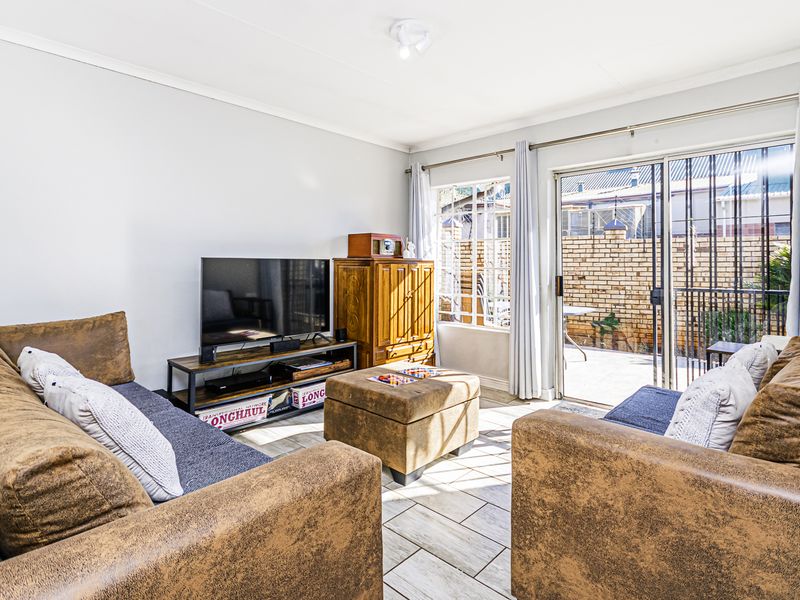 Bright living room featuring tiled flooring and large sliding glass doors providing direct access to the rear patio area.