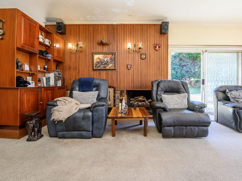 Living room featuring wood paneling, built-in cabinetry, and a fireplace, with sliding glass doors providing access to the outdoor area.